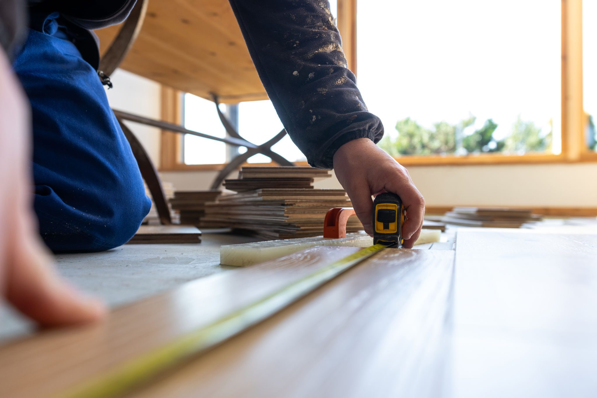 Person measuring wood with a tape measure during a woodworking project.