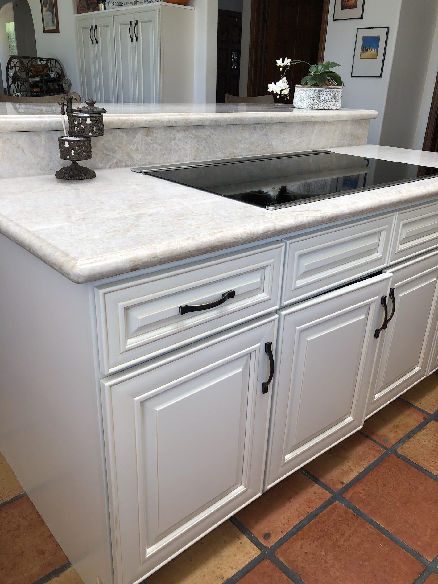 White kitchen cabinets with black handles and a marble countertop.