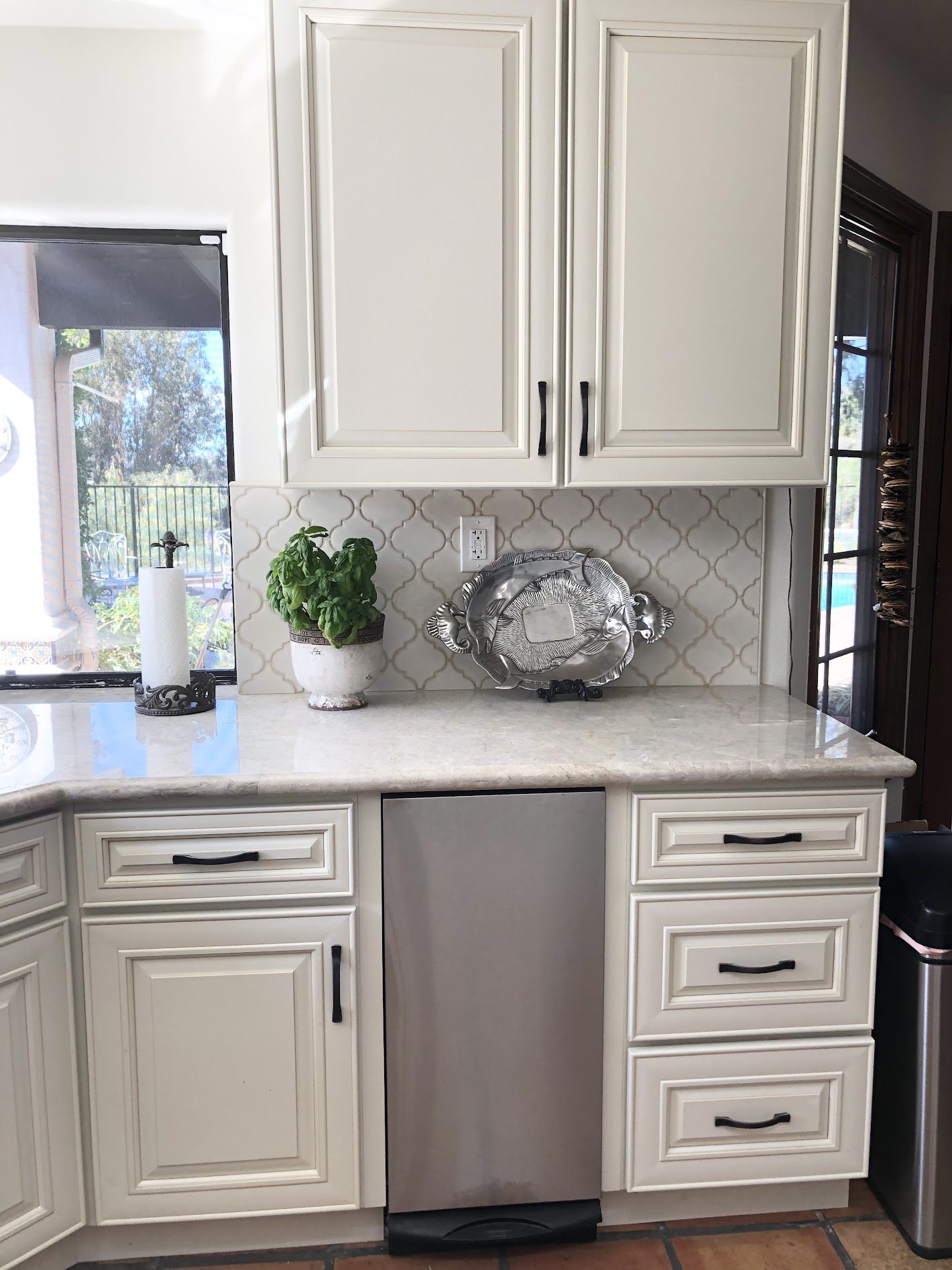 Bright kitchen counter with white cabinets, marble countertop, and decorative items.