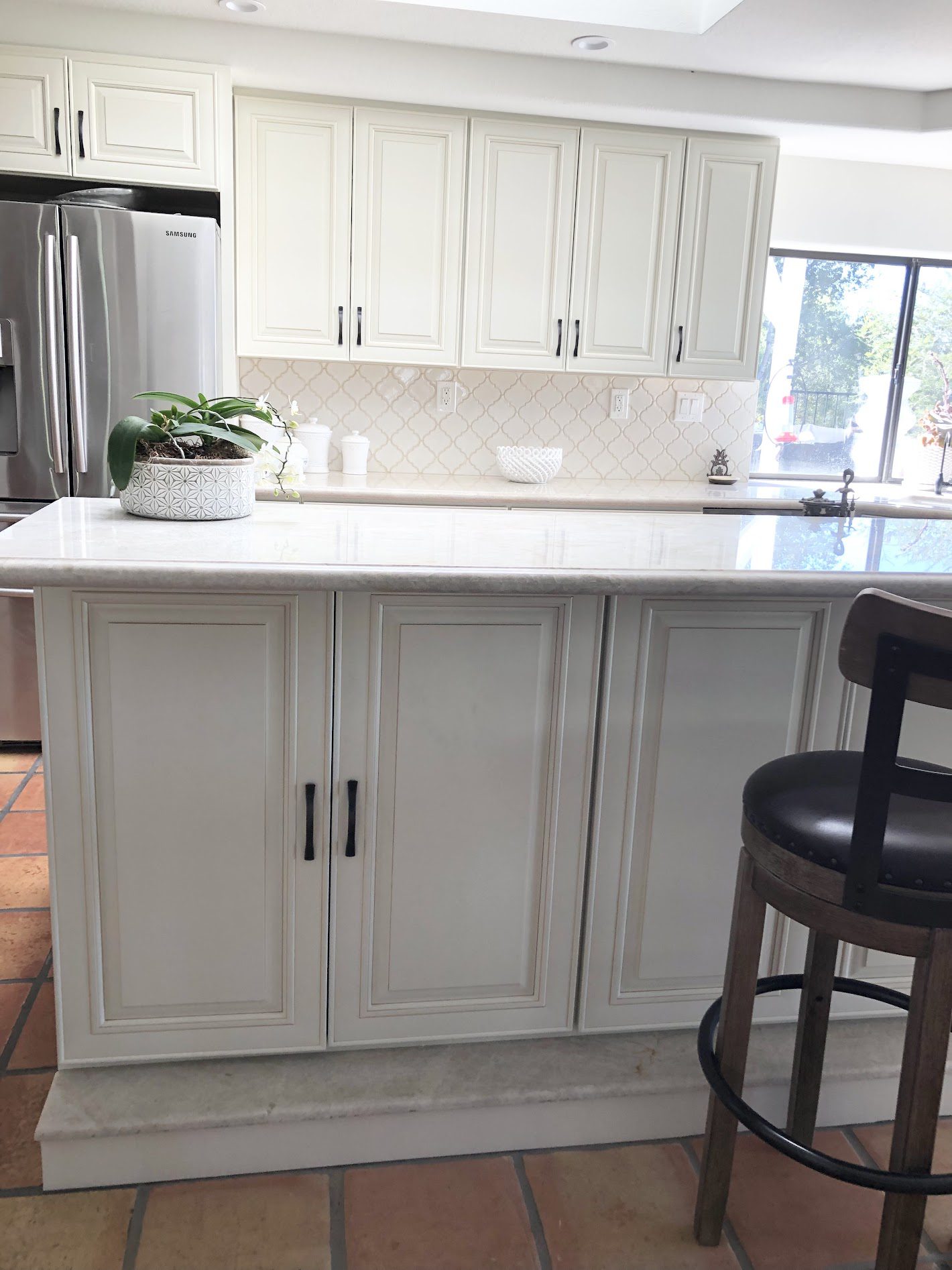 Modern kitchen island with white cabinets and marble countertop.