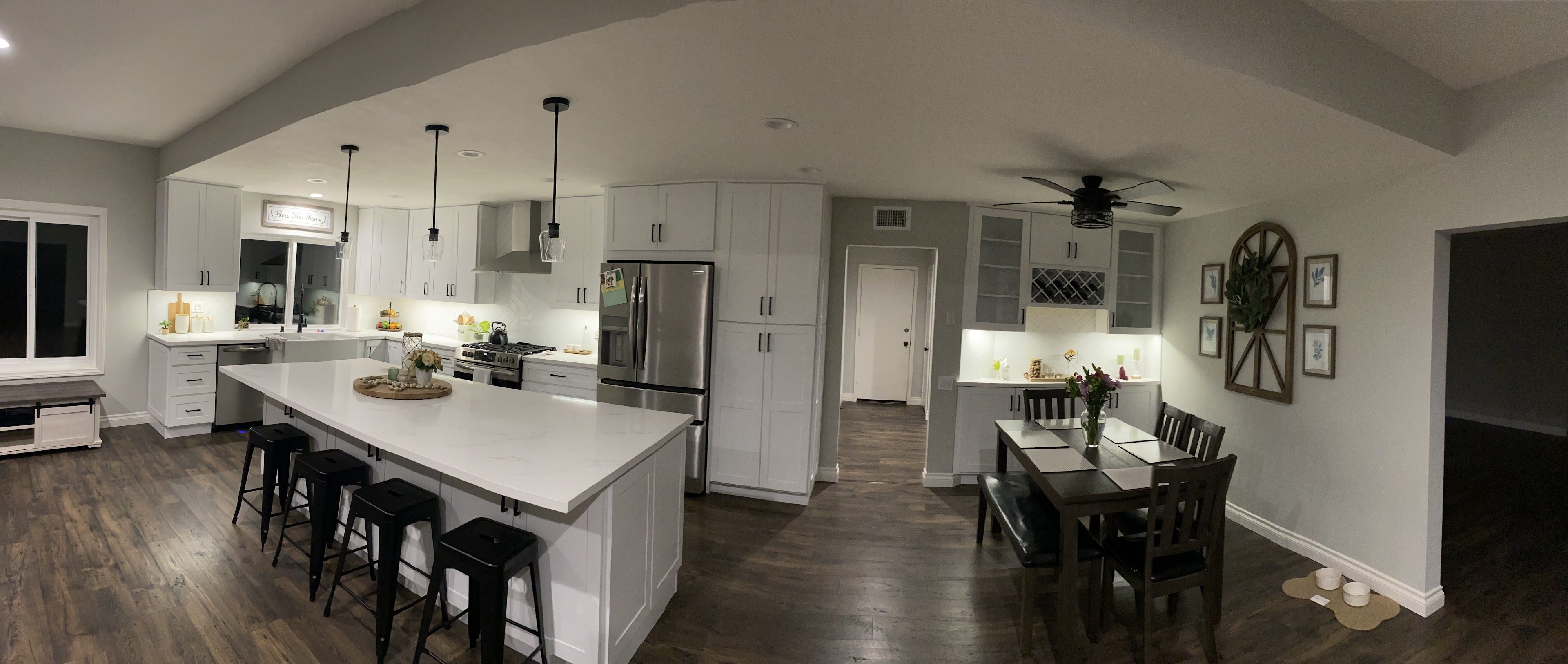 Modern kitchen and dining area with white cabinetry and dark wood floors.